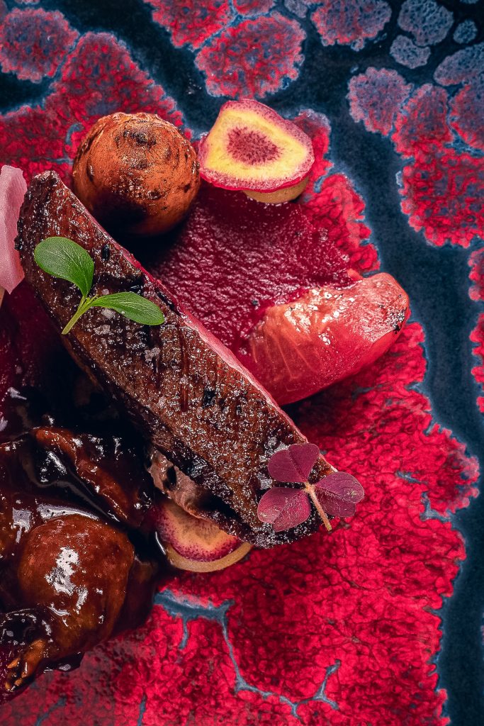 Création de viande et fruits rouges sur une assiette corail