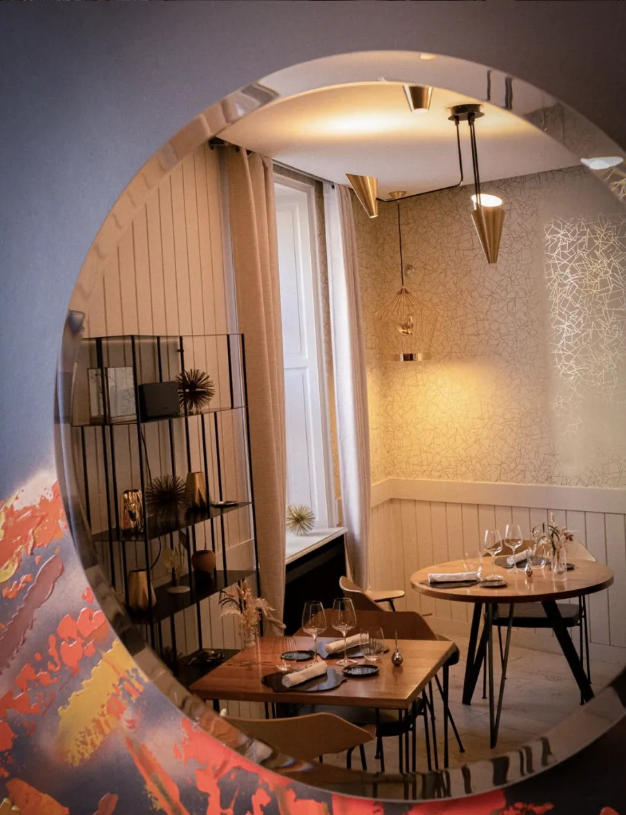 La salle du restaurant L’Évidence à Montbazon, vue à travers un miroir rond